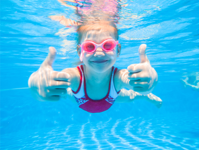 Girl showing thumbs up under water in a pool