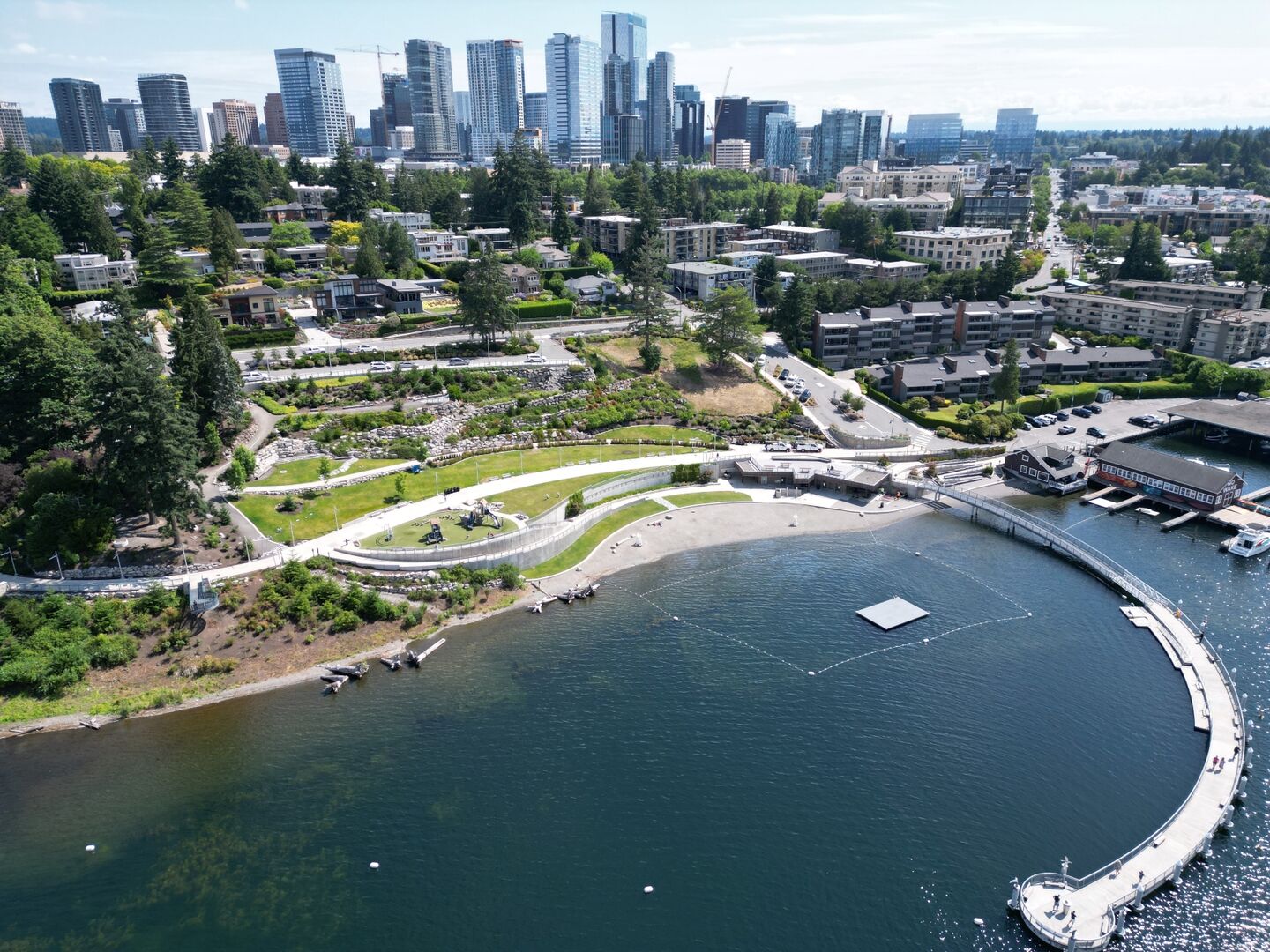 Aerial view of Meydenbauer Bay Park showing a large, curved pier, grassy areas, paths, and the historic Whaling Building and Marina.