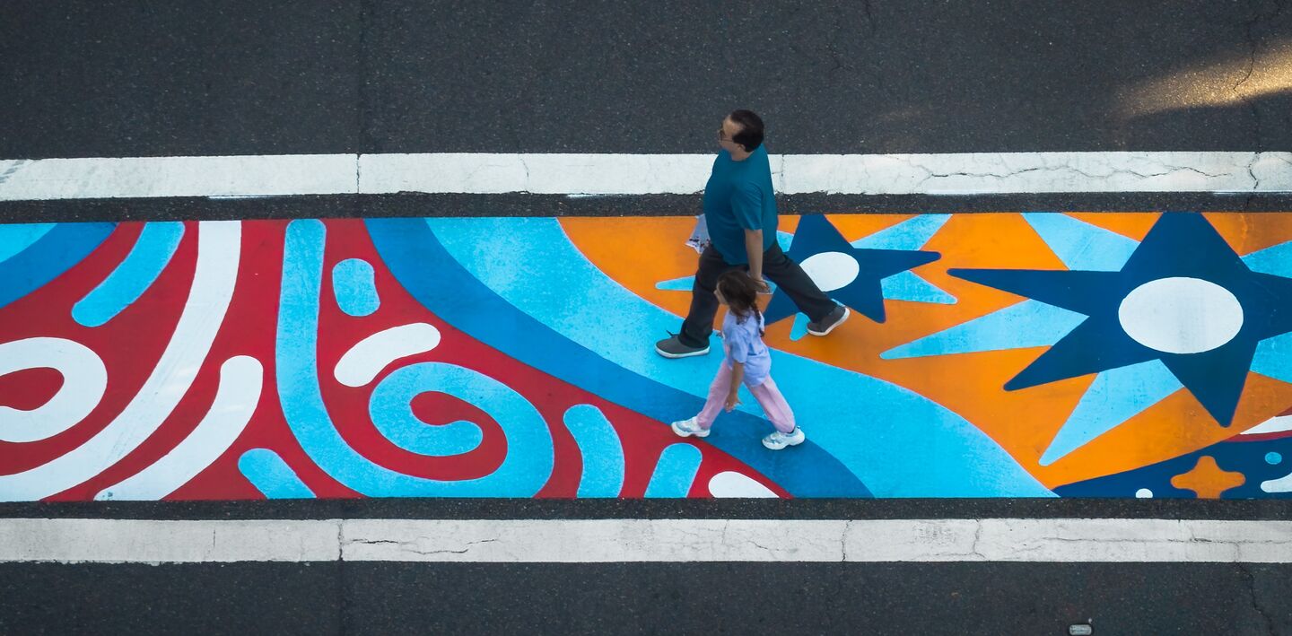 Image of the painted crosswalk at 164th Aven NE and NE 24th Street. The abstract image uses blue, red, white and yellow.