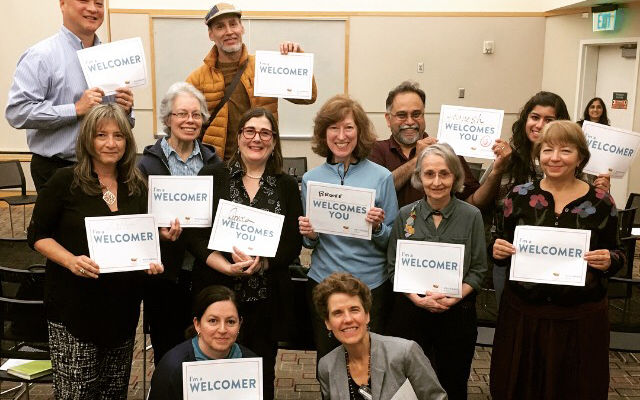 Participants at an Eastside Welcoming Week event hold signs that say "welcome."