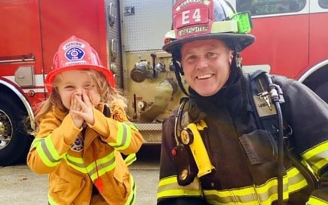 A little girl can't help but smile with a firefighter.