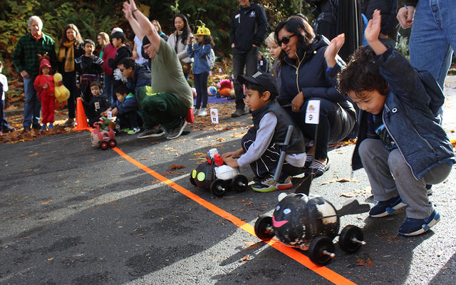 The children are gathered at the starting line with their pumpkin racers.