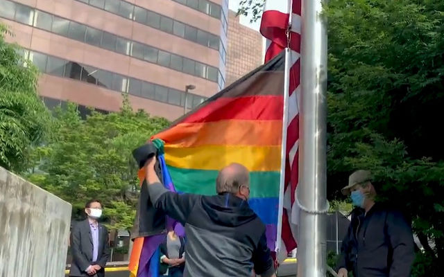 Staff raise a rainbow flag at City Hall for Pride Month.