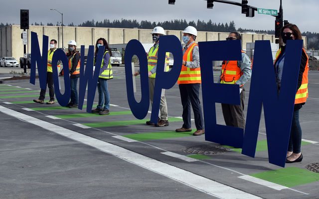 People hold up large letters spelling "open" as they stand on Northeast Spring Boulevard