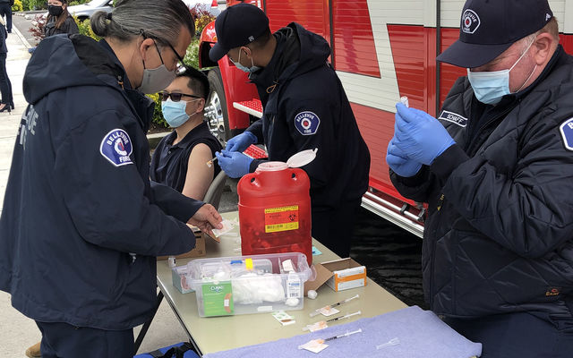 Firefighter-medics administer a COVID-19 vaccine at a pop-up clinic at Downtown Park.
