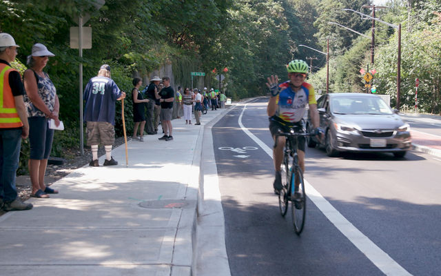 A cyclist waves from a new bike lane.