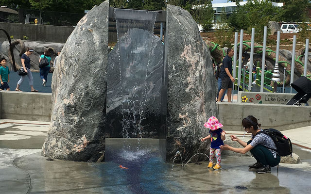 A little girl checks out the waterfall at the Inspiration Playground at Downtown Park.