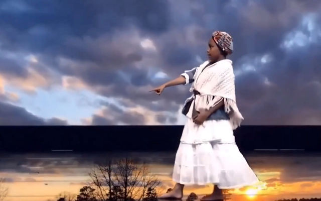 DianaStarr Raynell performs in front of a video backdrop for a presentation about Americans' passage from slavery.