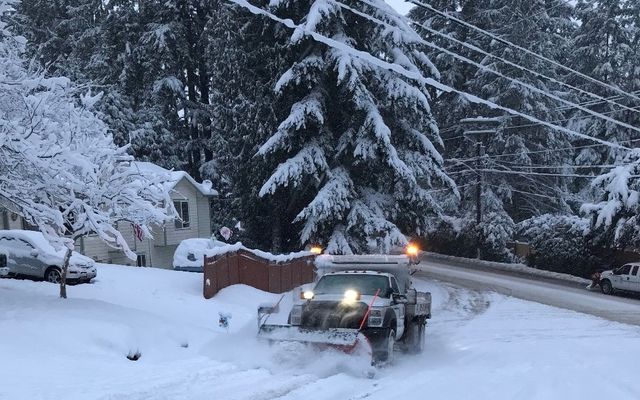 A snowplow clears a neighborhood street.