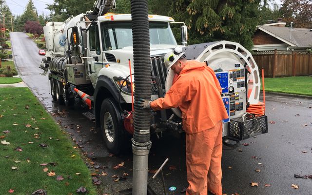 Utilities staff use a vactor to clear a catch basin.