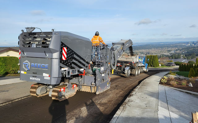 Contractors grind the top layer of road pavement.