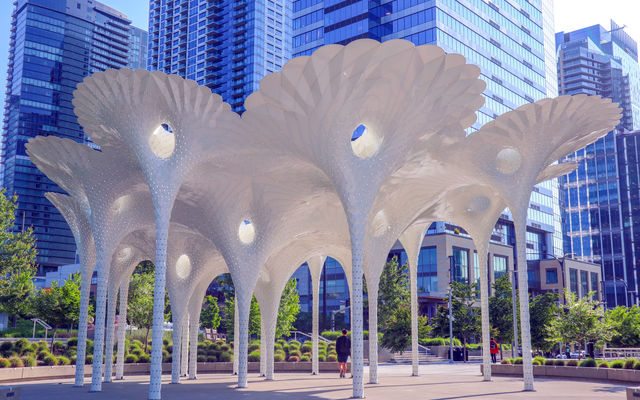 The artwork Piloti stands in the sun with people walking under it. Photo by Bellevue Downtown Association
