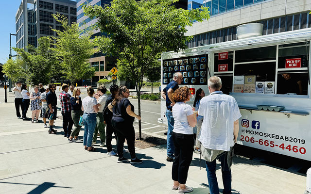 People line up for lunch at Momo's Kebabs food truck, which is parked at City Hall..