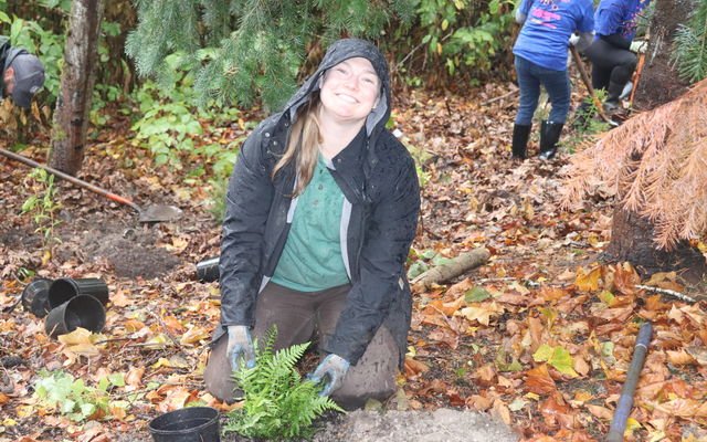 A woman smiles while planting a fern as part of Arbor Day in 2022.