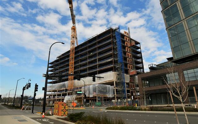 A multi-story building is partially constructed and still in construction phase with no exterior walls. A crane is in the foreground.