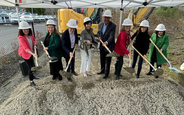 Officials with the City of Bellevue, Amazon, Bridge Housing and King County dig into a pile of dirt with shiny shovels.