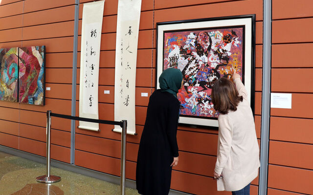 People look at an painting hung at City Hall for the Asian American Native Hawaiian and Pacific Islander heritage celebration.
