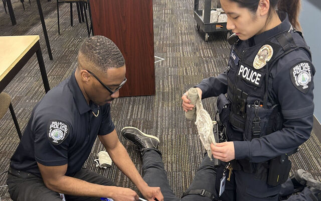 Two police officers train in medical trauma, practicing on a colleague.