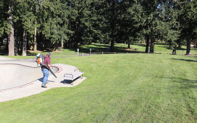 A man with a leaf blower tends to Crossroad Park.