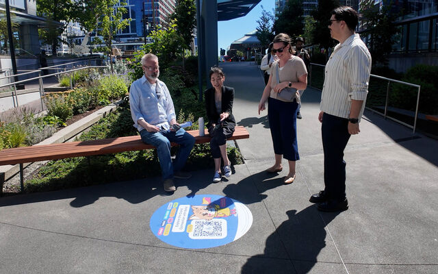 Four people look at a sidewalk decal in downtown Bellevue.