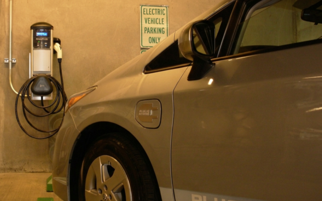 An electric vehicle is plugged into a parking garage charging station.