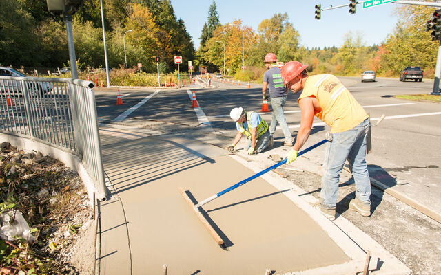 Photo of a worker smoothing concrete on a new sidewalk
