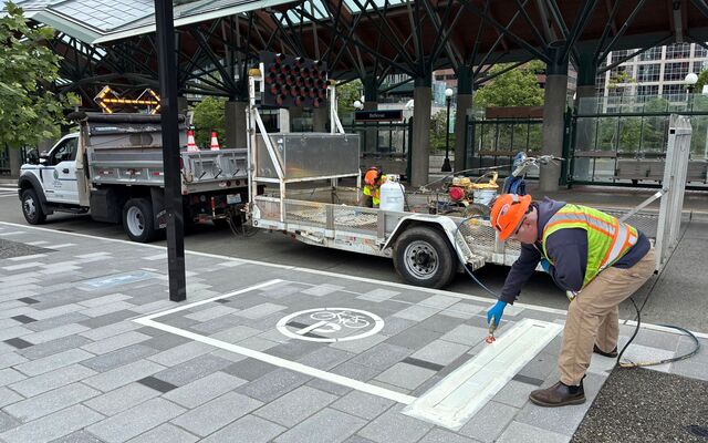 A contractor marks a large rectangle on a Bellevue sidewalk where Lime devices should be parked.