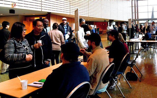 City staff at tables on the City Hall concourse meet with people walking around the space.