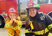 A little girl can't help but smile with a firefighter.