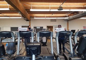 Staff at the fitness center hold signs that together say, "Welcome back."