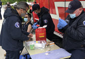 Firefighter-medics administer a COVID-19 vaccine at a pop-up clinic at Downtown Park.