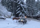 A snowplow clears a neighborhood street.
