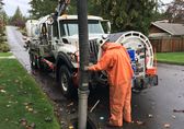 Utilities staff use a vactor to clear a catch basin.