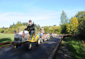 A man on a tractor pulls a line of little cars with children in them at the Kelsey Creek Farm Fair.