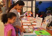 A mother and child look at a nonprofit organization's materials at a resource fair.ming Week resource fair