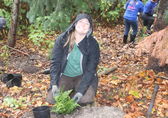 A woman smiles while planting a fern as part of Arbor Day in 2022.