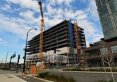 A multi-story building is partially constructed and still in construction phase with no exterior walls. A crane is in the foreground. 