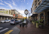 Photo of block on Old Main St. showing clock, businesses and cars on road in downtown Bellevue. 