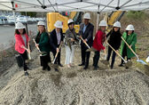 Officials with the City of Bellevue, Amazon, Bridge Housing and King County dig into a pile of dirt with shiny shovels.