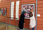 People look at an painting hung at City Hall for the Asian American Native Hawaiian and Pacific Islander heritage celebration.