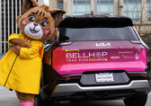 Belle the Bobcat, Visit Bellevue's mascot, leans against a BellHop shuttle.