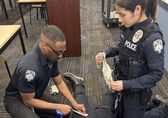 Two police officers train in medical trauma, practicing on a colleague.