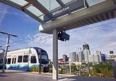 A light rail train arrives at the Wilburton station with downtown in the background.