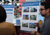 A Bellevue employee explains the city's affordable housing strategy to a woman as he stands by a board showing pictures of housing.