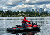 A firefighter rides a jet ski in Lake Washington, with downtown Bellevue in the background.