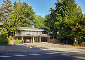 Multifamily housing that looks like a duplex or quadruplex stands between trees on a Bellevue street.