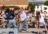 Young people dance in front of a crowd on the City Hall plaza.