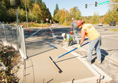 Photo of a worker smoothing concrete on a new sidewalk