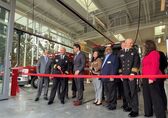 The mayor, deputy mayor and other councilmembers stand with the fire chief behind a red ribbon in the Fire Station 10 bay.