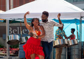 A couple dances, with a band behind them under a canopy, at Swing Arts Foundation's free jazz and swing dance lesson social at City Hall Plaza. 